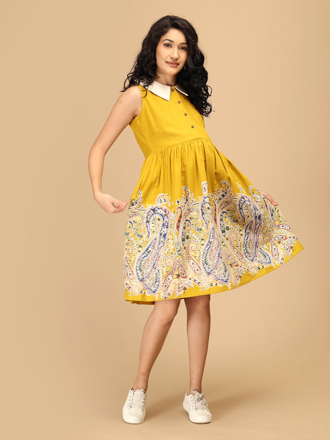 Pregnant woman in The Mom Store marigold maternity and nursing dress with paisley print flare.