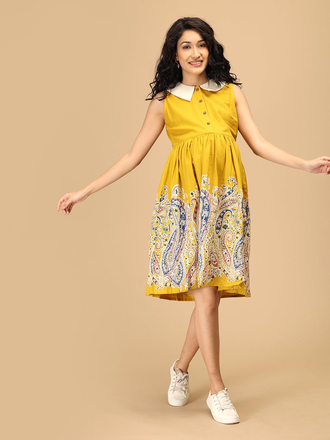 Pregnant woman wearing The Mom Store marigold maternity dress showing flowing printed skirt.