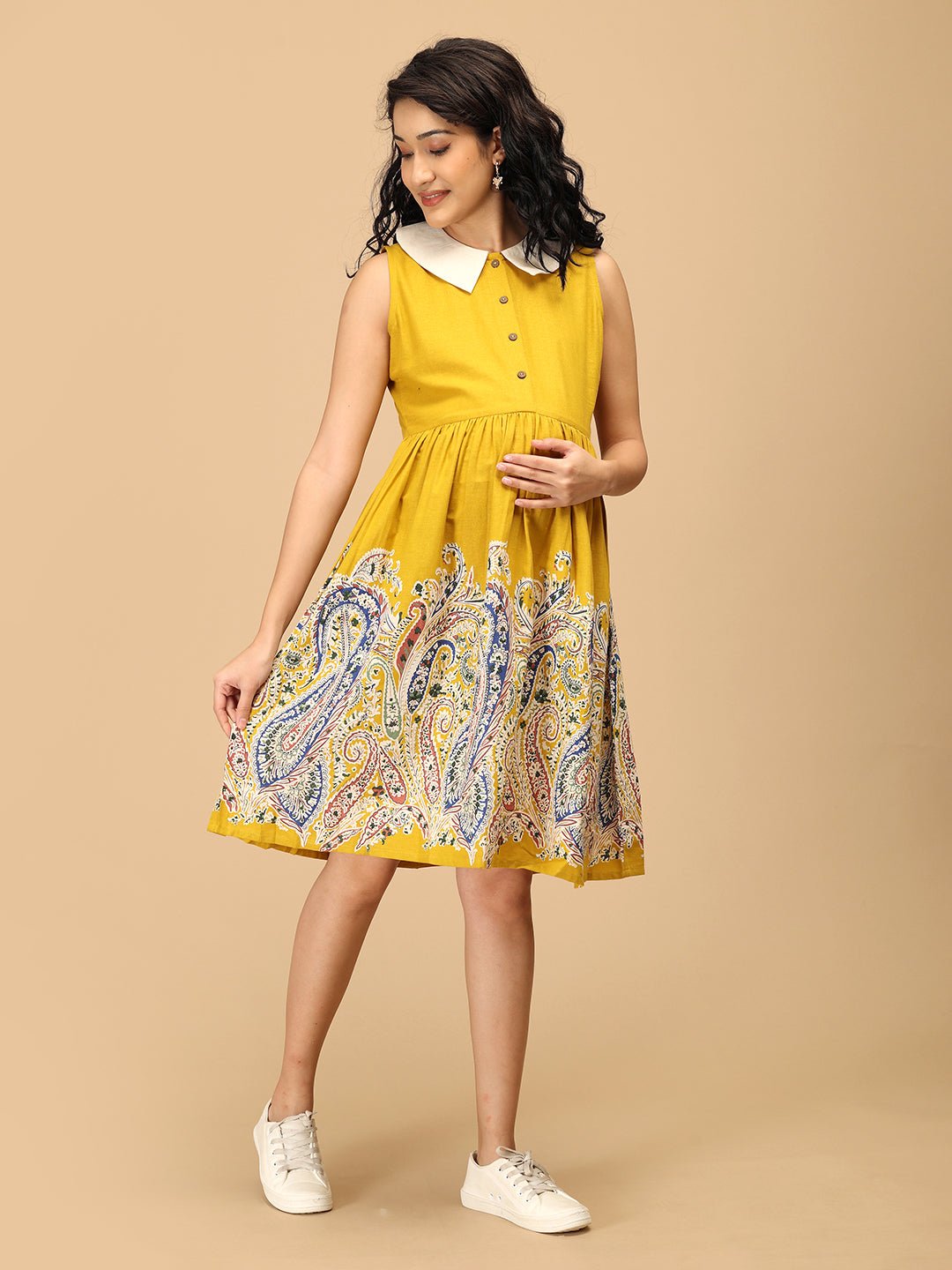 Pregnant woman in The Mom Store marigold nursing dress posing with bump-friendly fit.