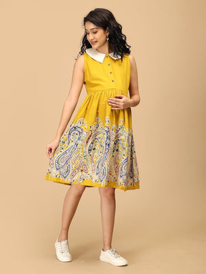 Pregnant woman in The Mom Store marigold nursing dress posing with bump-friendly fit.