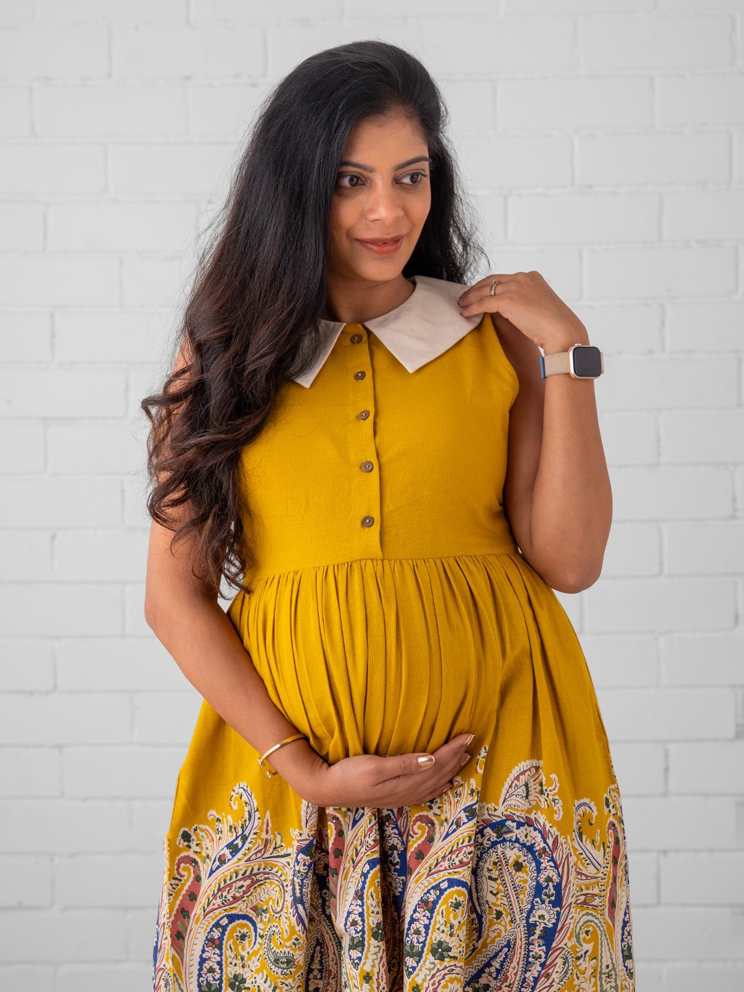 Expecting mom wearing sleeveless yellow maternity dress with paisley border – The Mom Store.