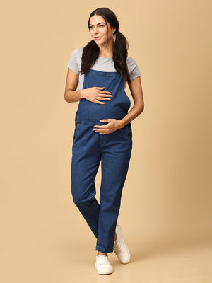 Relaxed pose of pregnant woman in The Mom Store blue Denim Maternity Dungaree with Side Buttons 