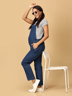 Side pose of pregnant woman in The Mom Store blue Denim Maternity Dungaree with Side Buttons and sunglasses