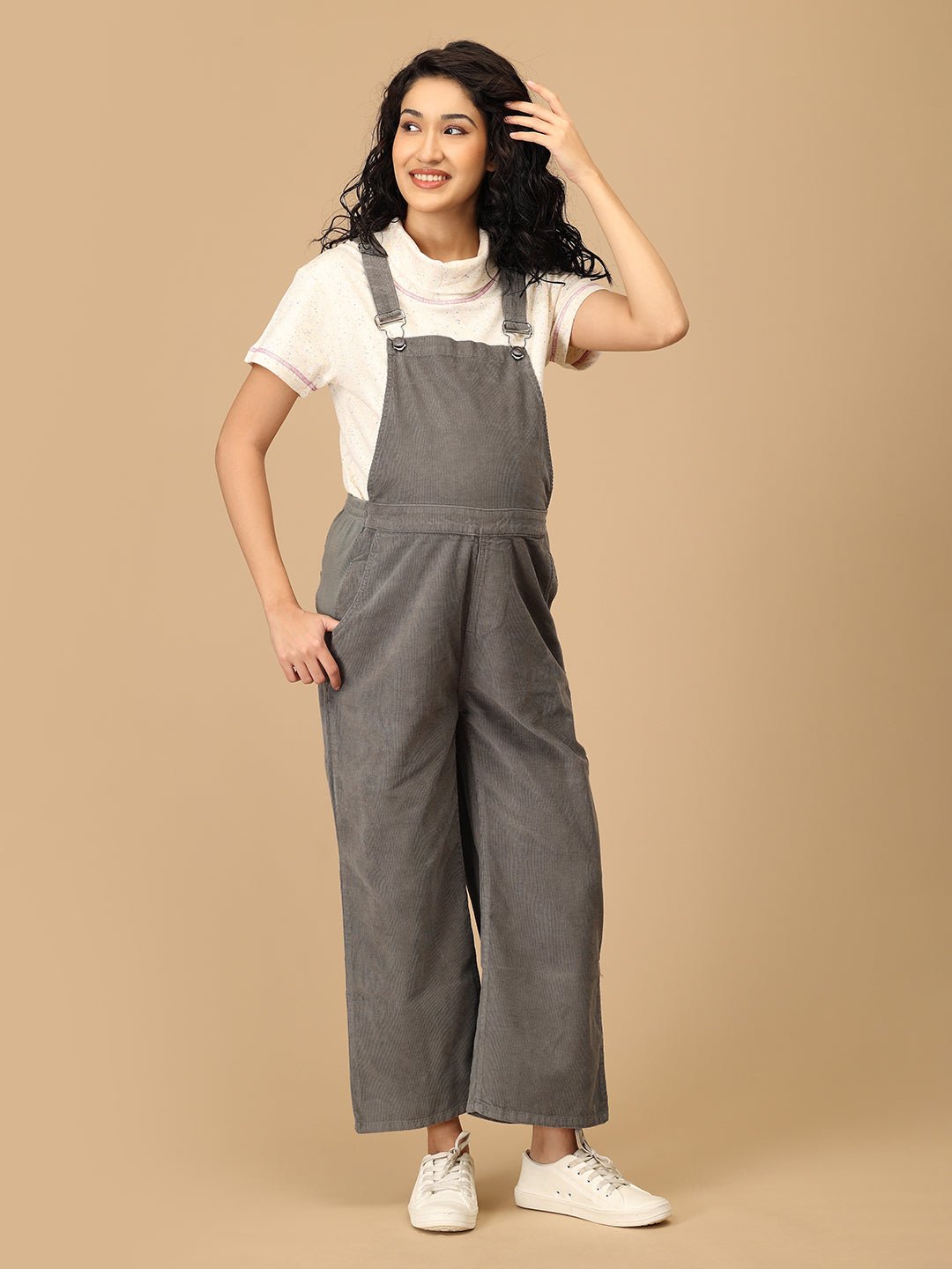 Front pose of pregnant woman in The Mom Store olive corduroy maternity dungaree with bump-friendly fit.