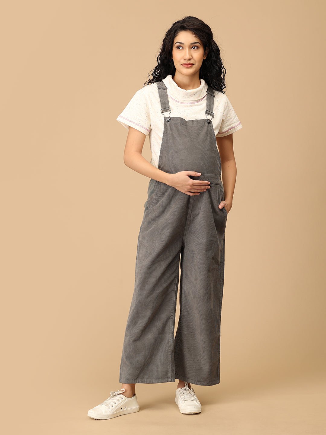 Pregnant woman in The Mom Store olive corduroy maternity dungaree with adjustable straps front view.