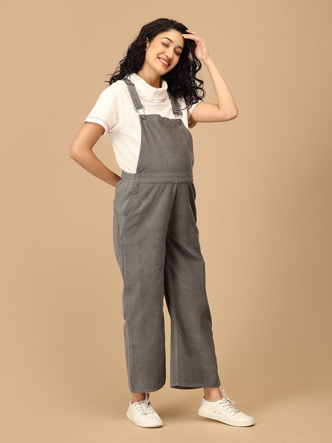 Pregnant woman wearing The Mom Store olive corduroy maternity dungaree with relaxed front stance.