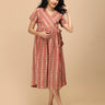 Peach Mirage Maternity and Nursing Dress – model in midi dress with side tie, smiling front view.