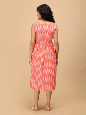 Back view of sleeveless peach maternity dress with all-over white print and knee-length hem.