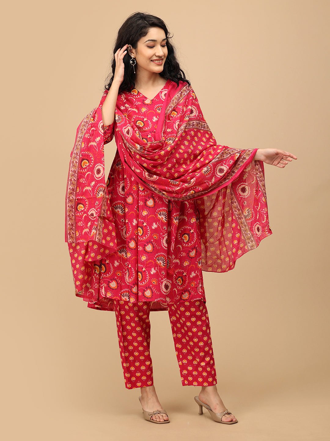 Angled front view of the printed pink maternity kurta paired with matching pants, model lightly touching her hair.