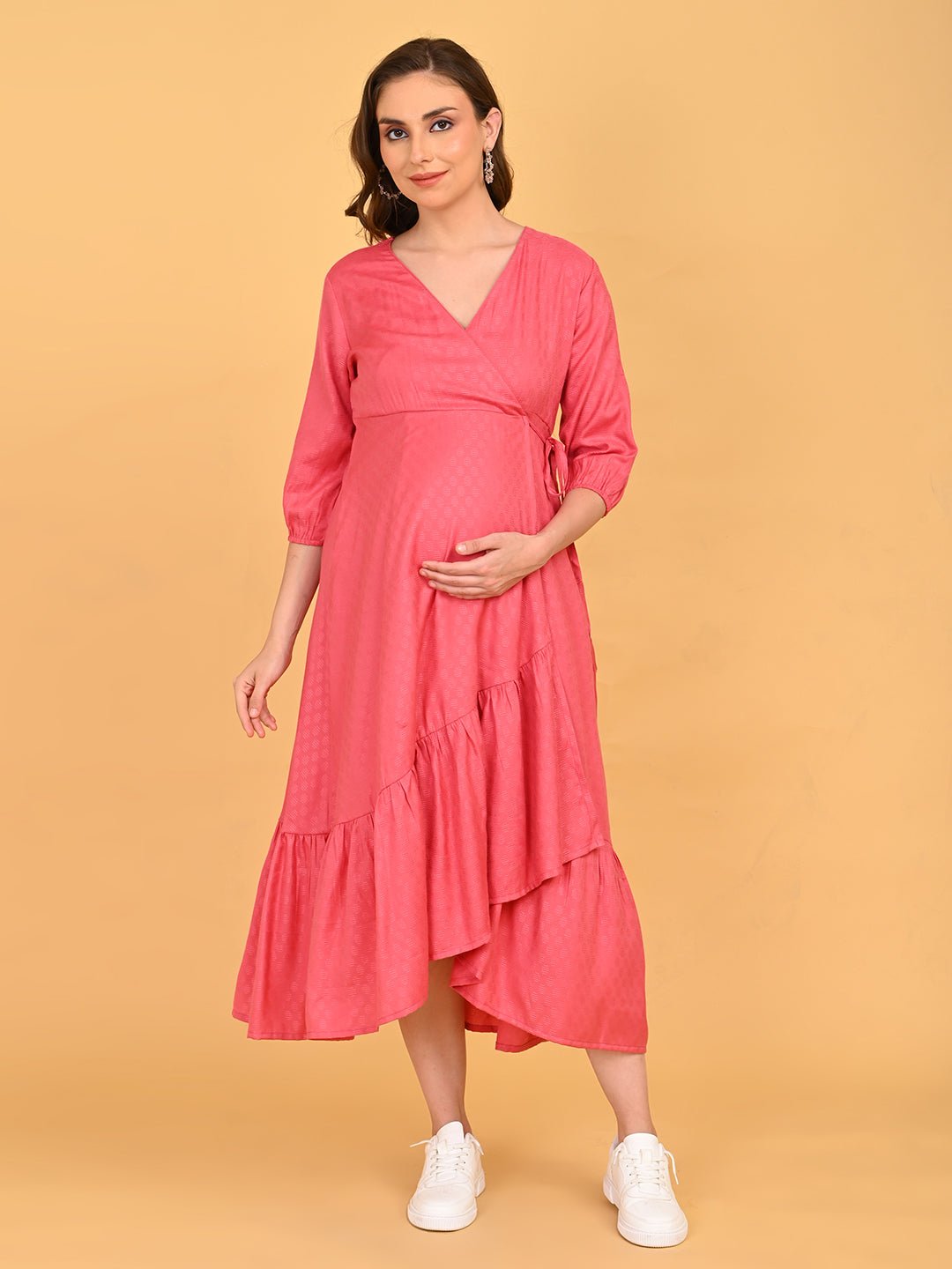 Pink to the Future Maternity Wrap Dress angled front pose with model holding baby bump, displaying flowy layered hemline.