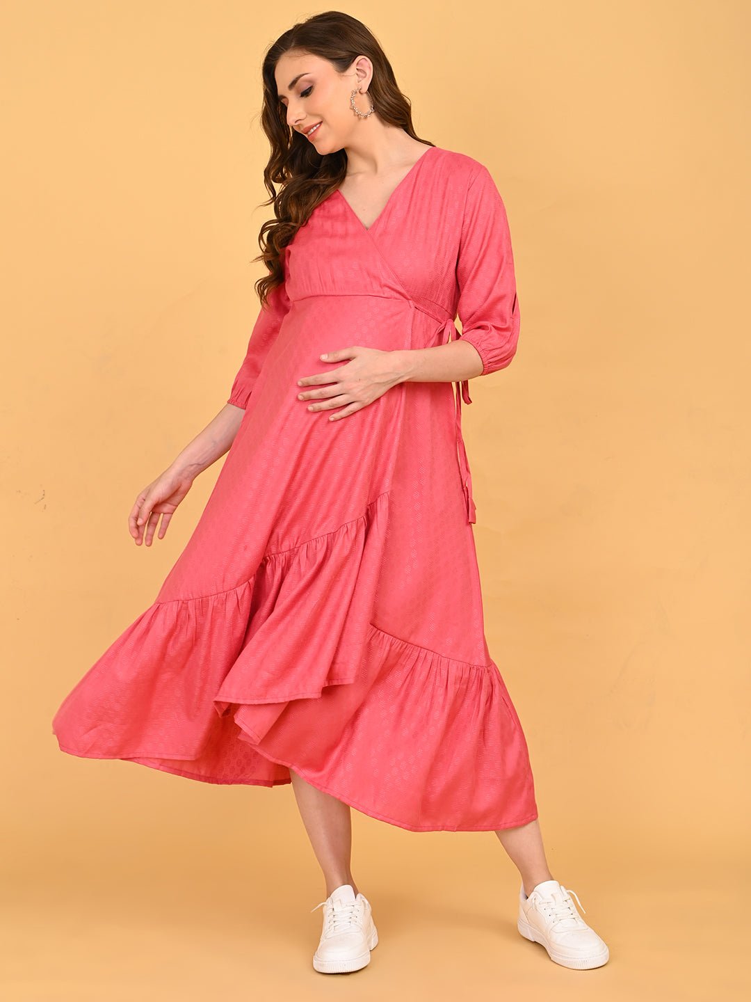 Pink to the Future Maternity Wrap Dress front view with hands on bump and pockets, showcasing soft textured finish and midi length.