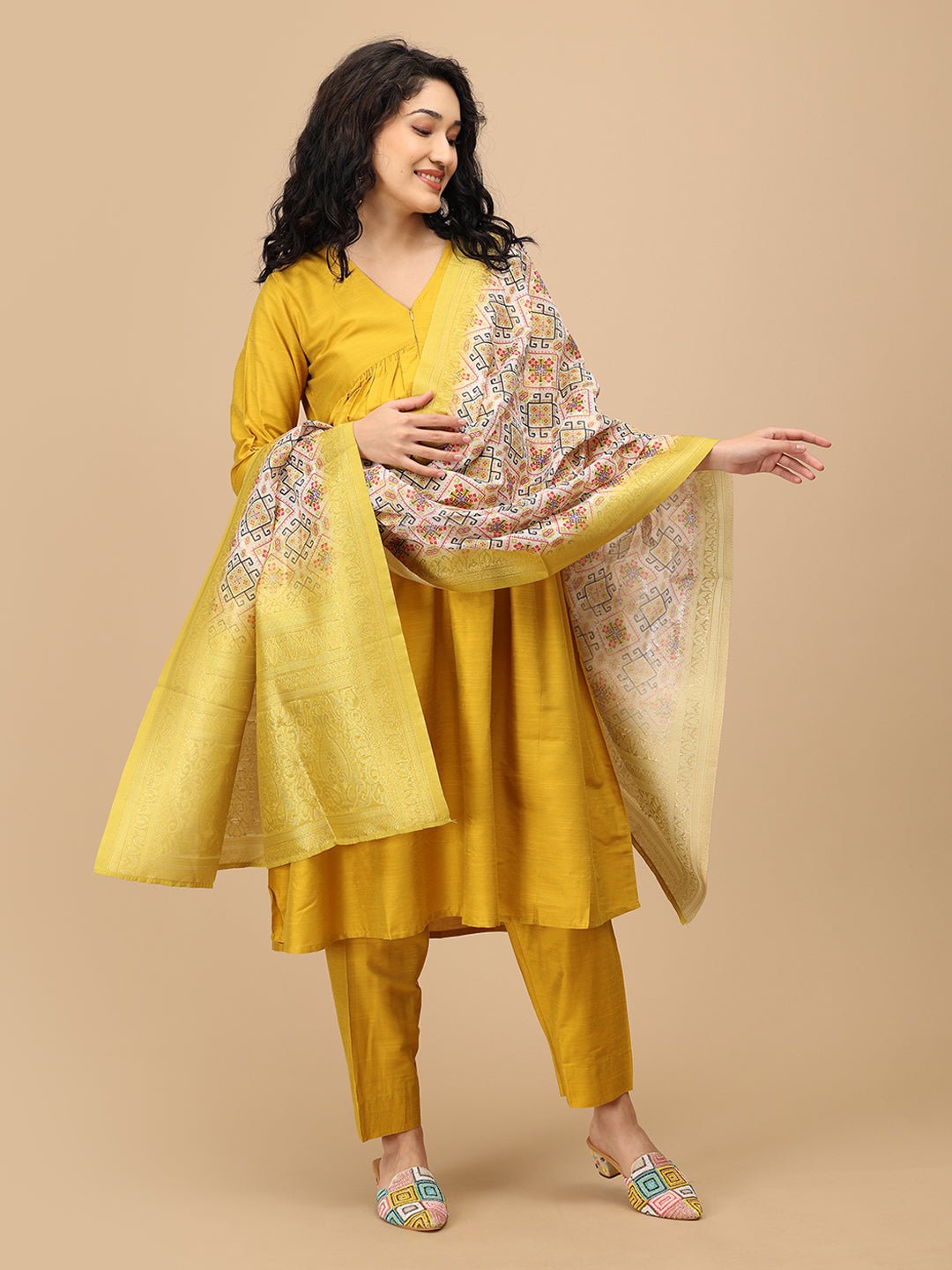 Pregnant woman in The Mom Store mustard silk maternity kurta set paired with geometric printed dupatta.