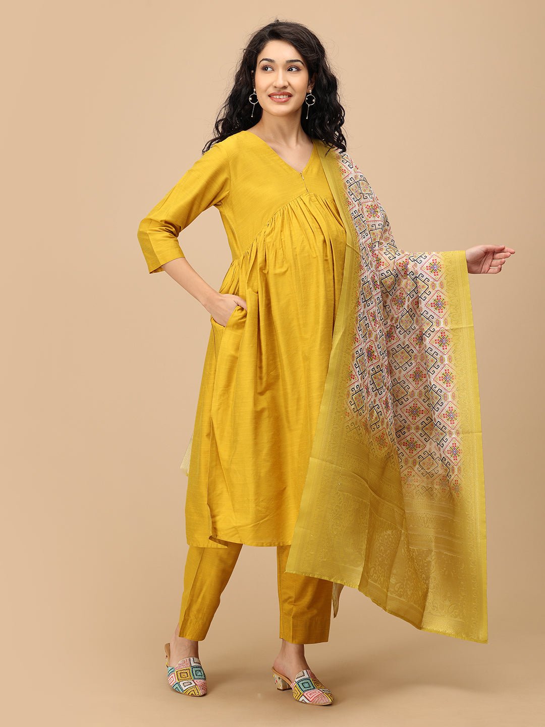 Smiling pregnant woman in The Mom Store mustard maternity silk kurta set showcasing printed dupatta.