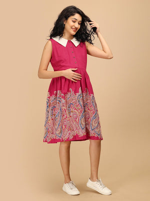 Model wearing the Ros√© Lane Maternity and Nursing Dress in pink with paisley border print, standing casually with one hand on baby bump.