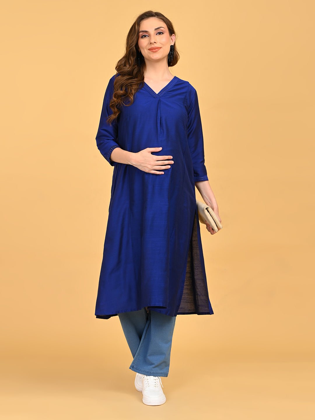 Pregnant model wearing royal blue embroidered maternity silk kurta with light blue pants and white sneakers.