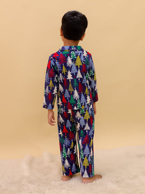 Back view of a little boy in The Mom Store Silent Night Christmas Pajama Set, showing the full pattern of festive Christmas trees on the navy blue pajama fabric.