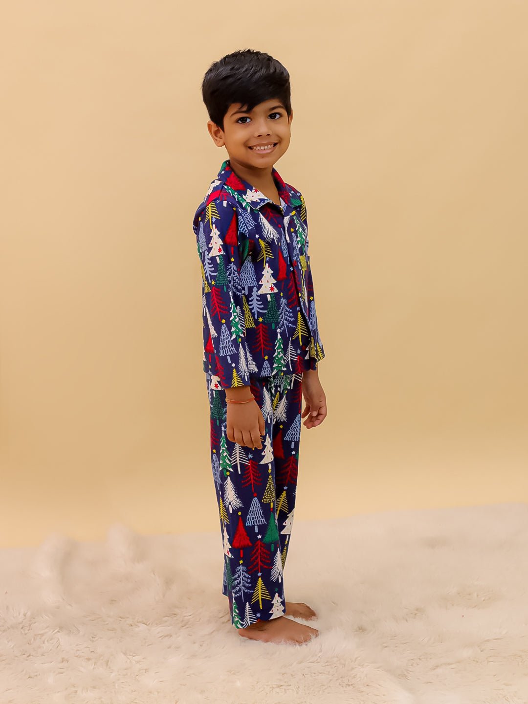 Another side angle of the boy in The Mom Store Silent Night Christmas Pajama Set, showcasing the colorful holiday-themed design and comfortable fit.