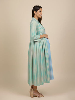 Side pose maternity and nursing outfit with green striped longline shacket over striped maxi dress.
