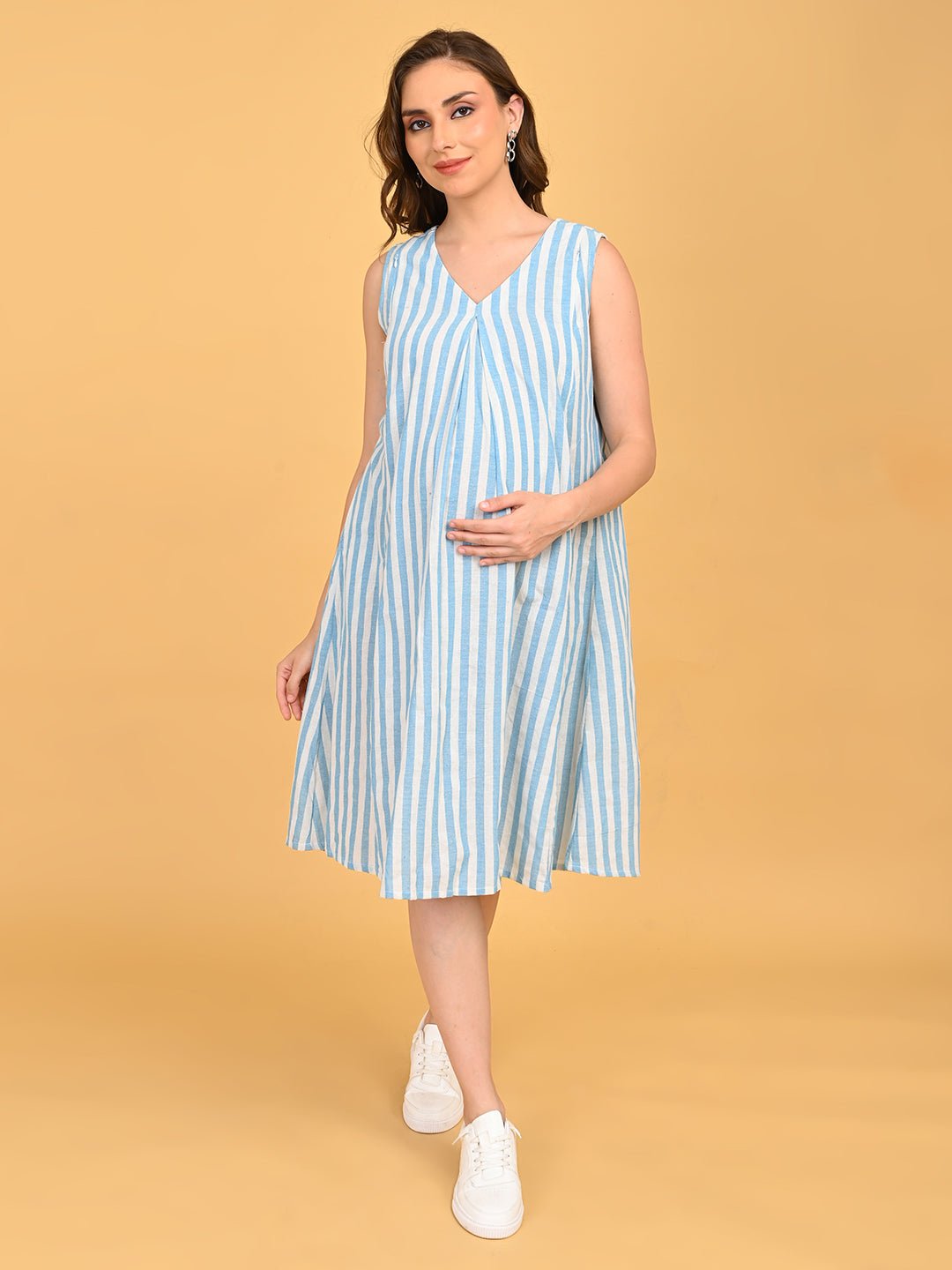 Pregnant model standing in blue striped nursing dress.