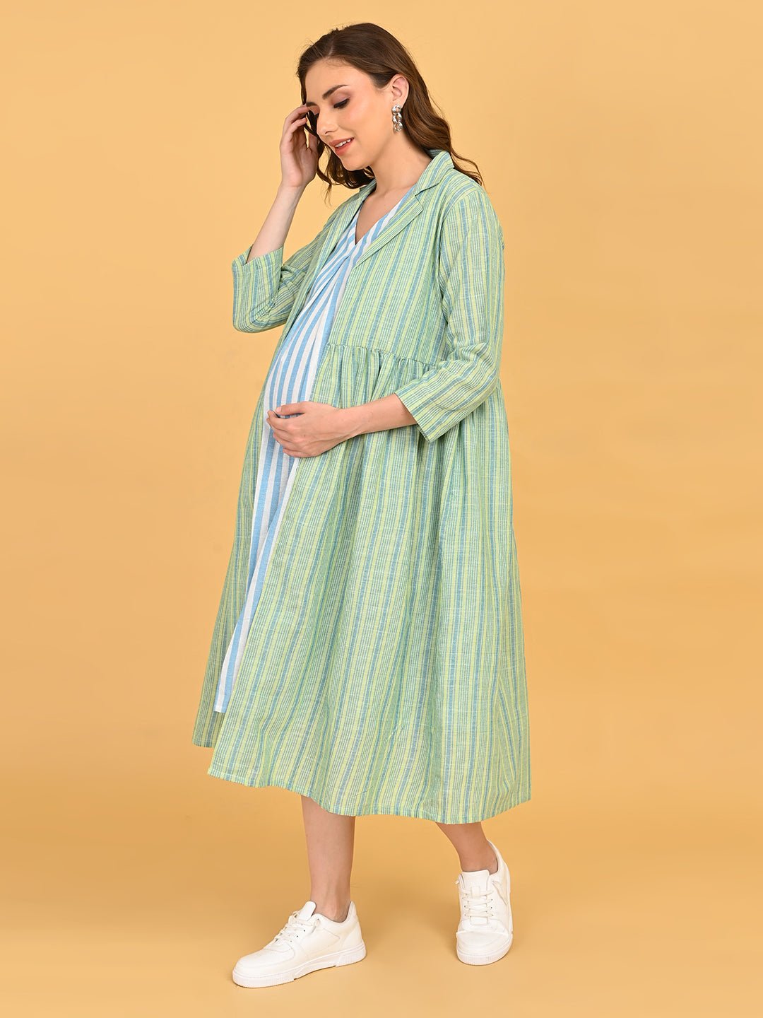 Pregnant model walking in blue and white striped maternity and nursing dress with relaxed A-line fit.