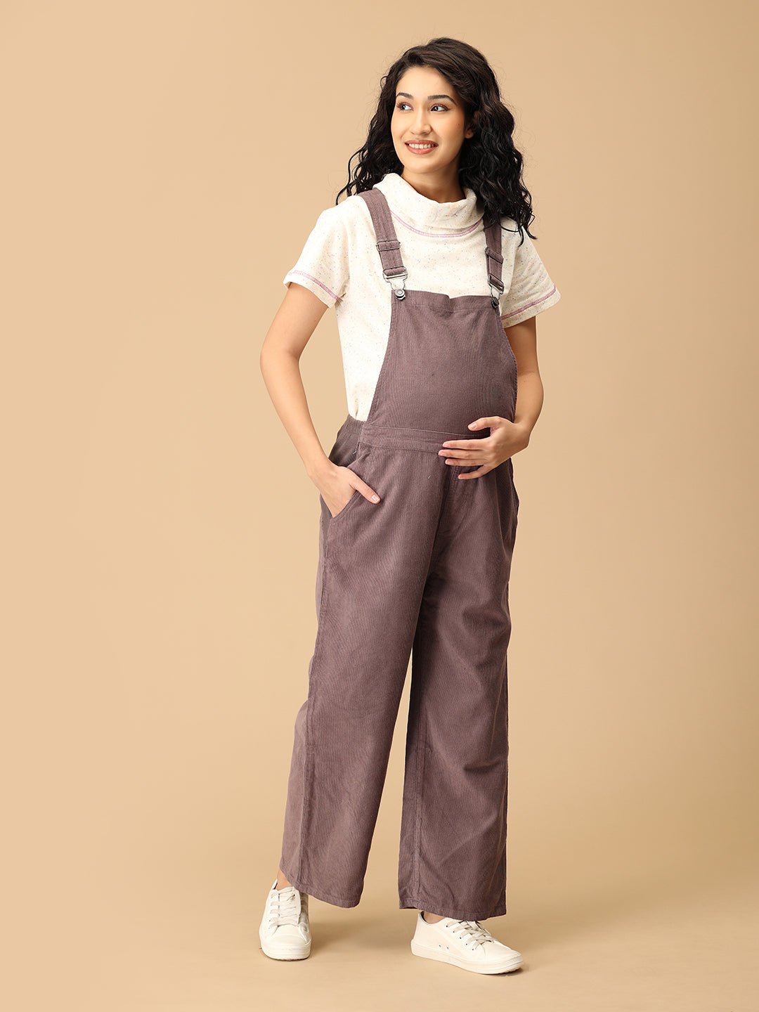 Pregnant woman in The Mom Store taupe corduroy maternity dungaree showing relaxed wide-leg style.