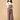 Pregnant woman posing in The Mom Store taupe corduroy maternity dungaree with adjustable straps.