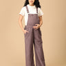 Pregnant woman posing in The Mom Store taupe corduroy maternity dungaree with adjustable straps.