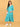 Turquoise Temptation Maternity Wrap Dress full-length front view with model holding baby bump, styled with white sneakers and crossbody bag.