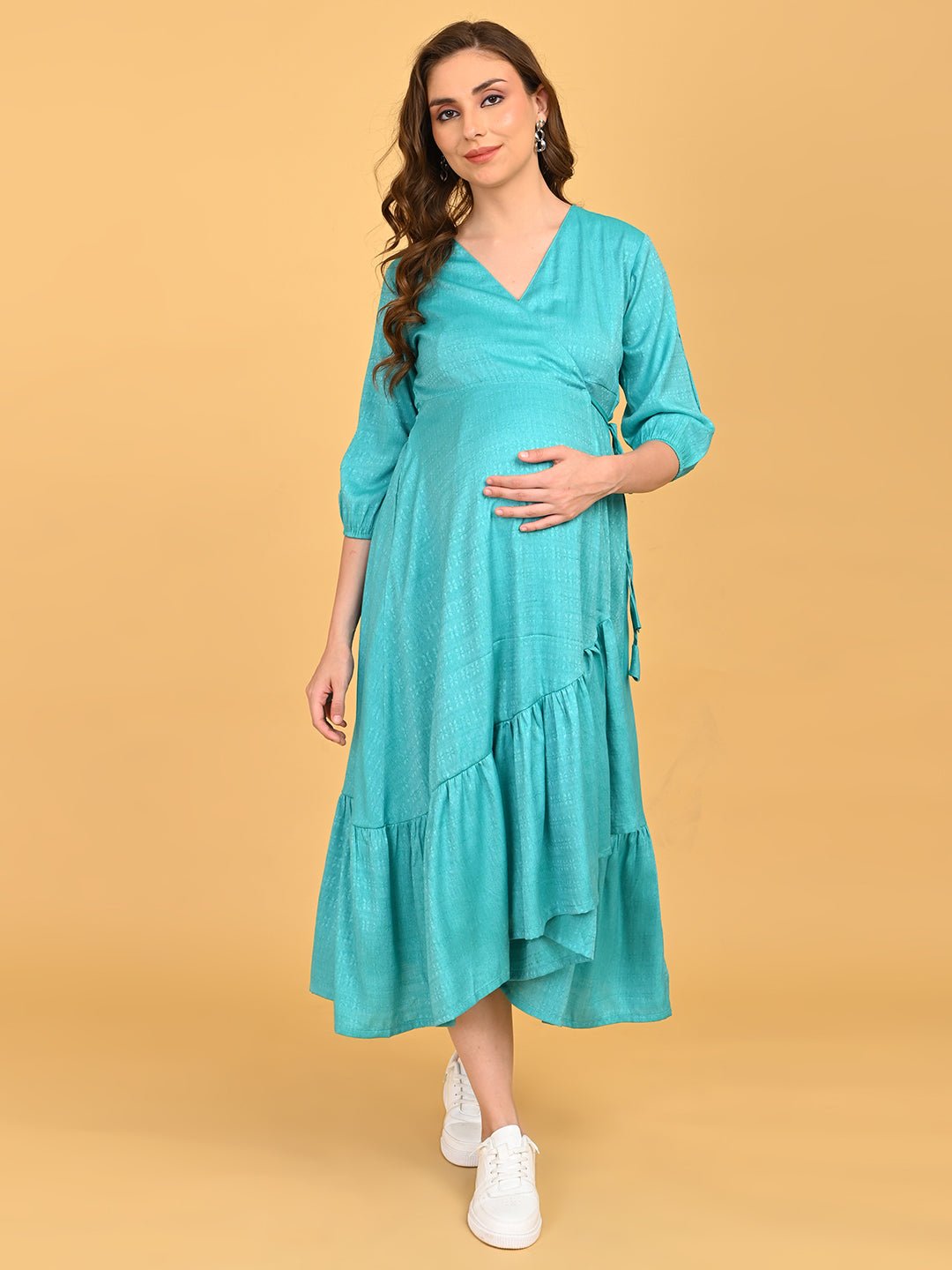 Turquoise Temptation Maternity Wrap Dress full-length walking pose showing asymmetrical hemline and casual sneaker styling.