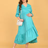 Turquoise Temptation Maternity Wrap Dress full-length front pose with model cradling bump, showcasing textured fabric and wrap design.