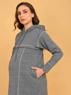 Upper body close-up of model wearing grey maternity hoodie dress with hood and drawstrings.