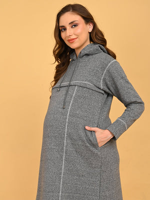 Side view of pregnant model in grey maternity hoodie dress highlighting baby bump fit and pocket detail.