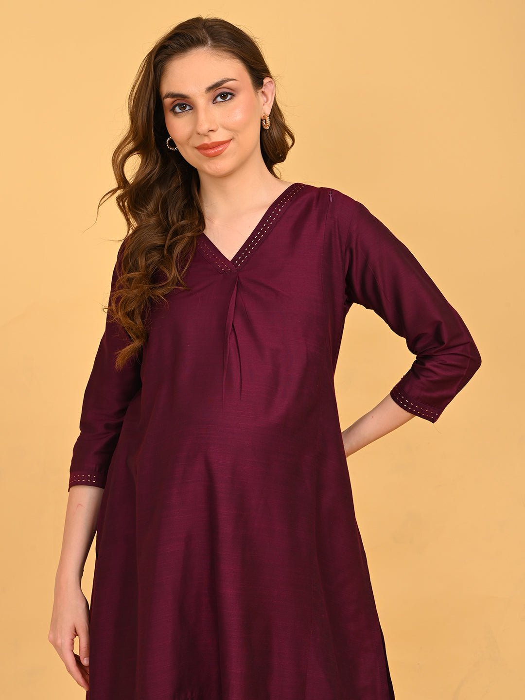 Upper body view of model wearing wine embroidered maternity silk kurta with V-neck and soft sheen fabric.