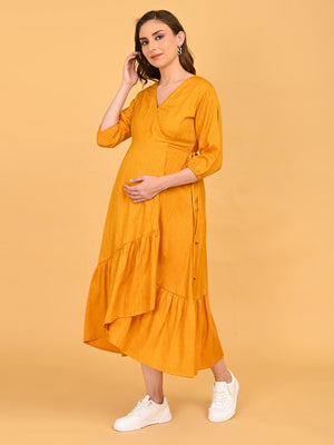 Side view of Heavily pregnant model posing with her hand over bump, yellow go go maternity wrap dress