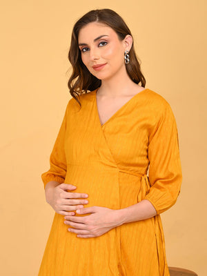Close up of Heavily pregnant model posing with her hand over bump, yellow go go maternity wrap dress