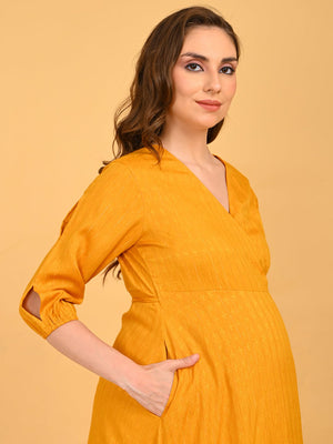 Portrait of a lady wearing yellow a go go Maternity Wrap Dress, standing with her hands inside the pockets